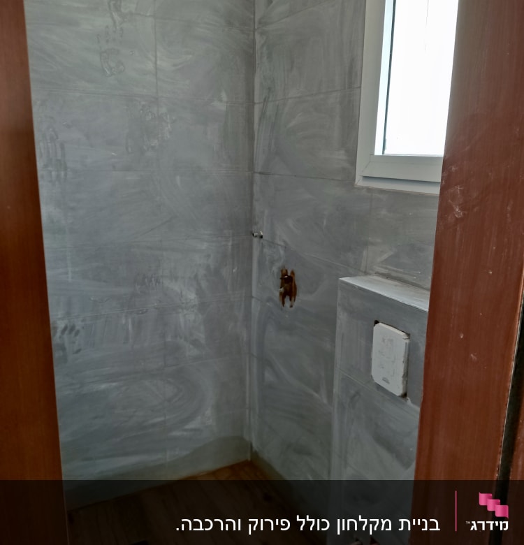 חדר אמבטיה בשיפוץ עם קירות אריחים אפורים